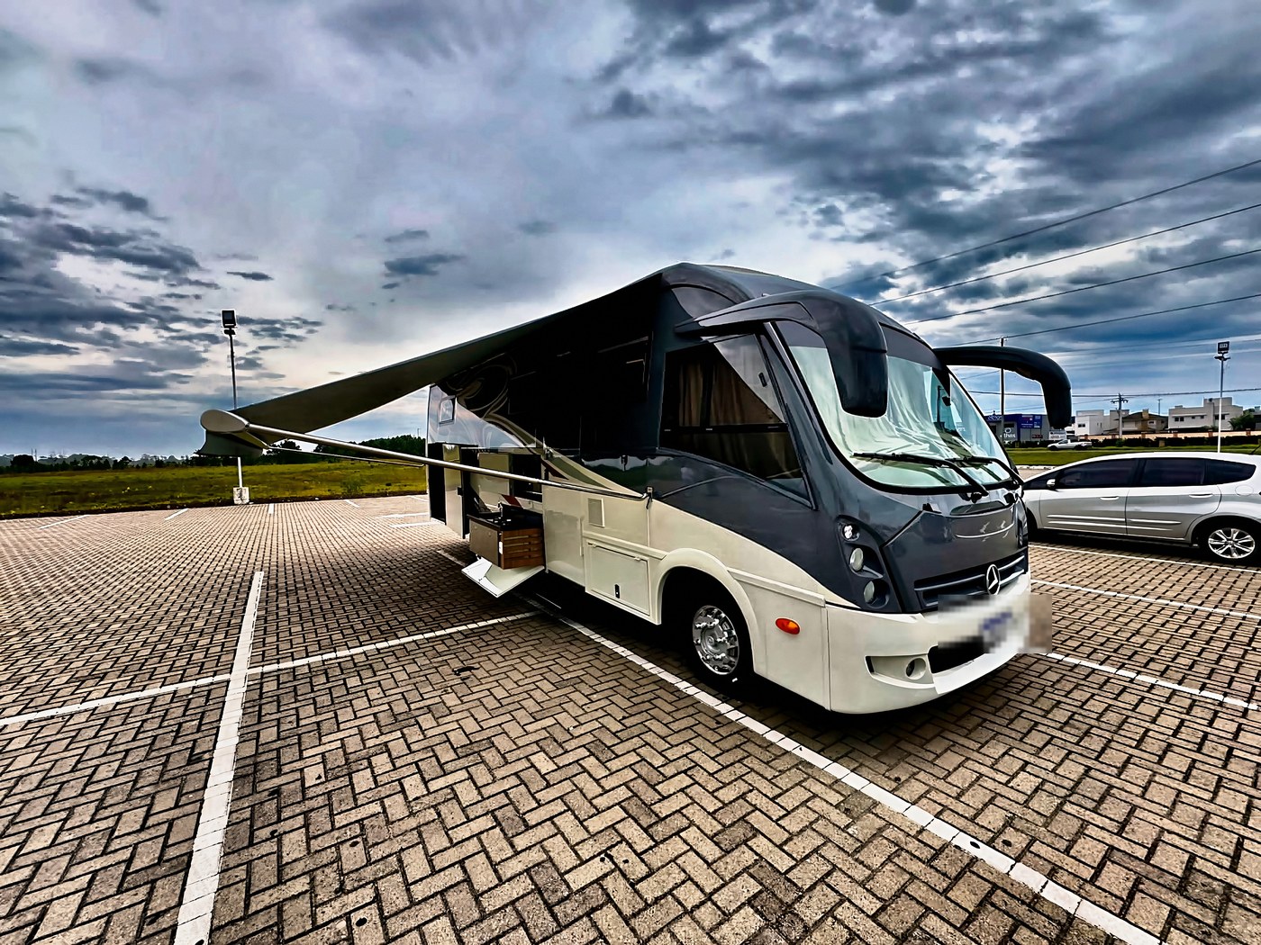 Motorhome Mercedes-Benz LO 916 estacionado, toldo aberto, céu de tempestade ao fundo